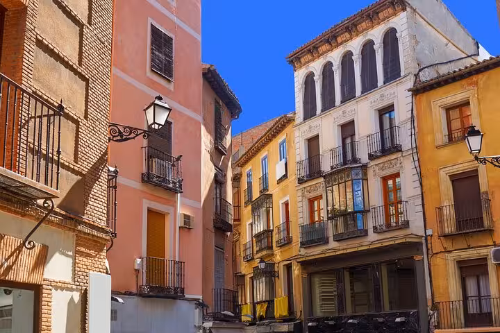 Charming historic buildings with colorful facades in Toledo's old town on a sunny day.