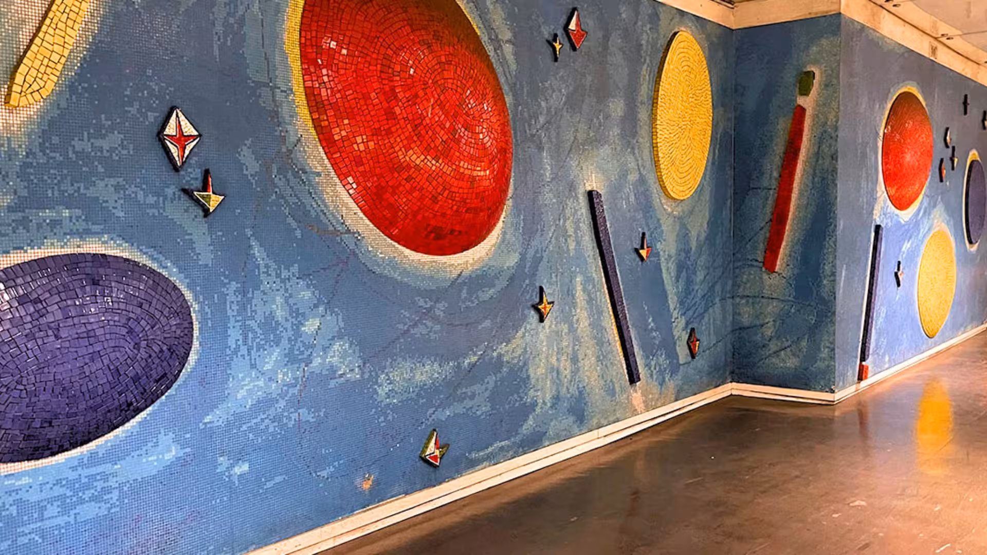 Vibrant mosaic art with colorful geometric shapes at Toledo metro station in Naples, featuring red, yellow, and blue designs.