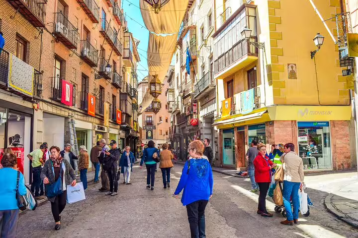 Travelers strolling a lively Toledo old town street on a private half-day minivan tour from Madrid