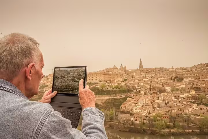 Traveler capturing the panoramic view of Toledo, Spain, highlighting a scenic stop on the Lisbon to Madrid private transfer tour.