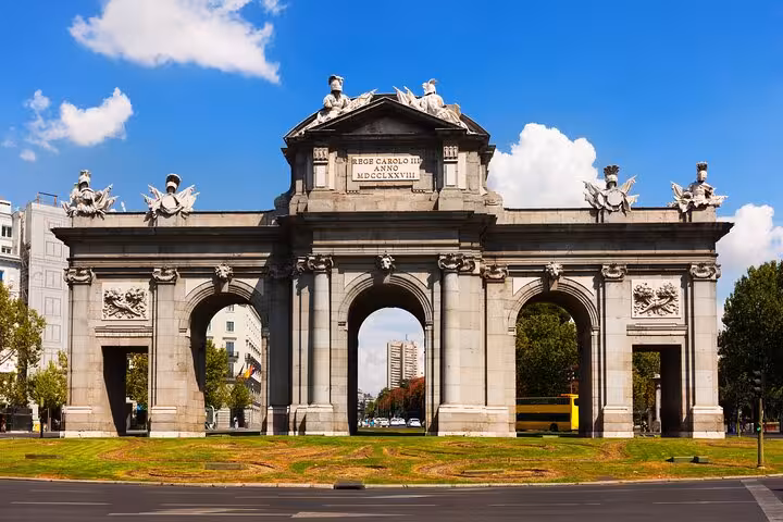 Majestic stone archway of Puerta de Alcalá under blue skies in Toledo, Spain.