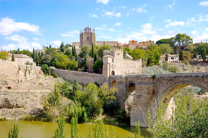 Scenic view of the historic San Martín Bridge and surrounding lush greenery in Toledo, perfect for a day trip from Madrid.