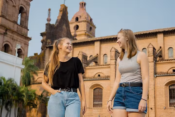 Two women enjoying a sunny day in Toledo, Spain, with historic architecture in the background during a guided city tour.