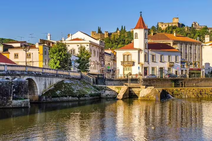 Scenic view of Tomar's historic architecture and river, featuring the Convent of Christ, on the Tomar and Almourol tour.
