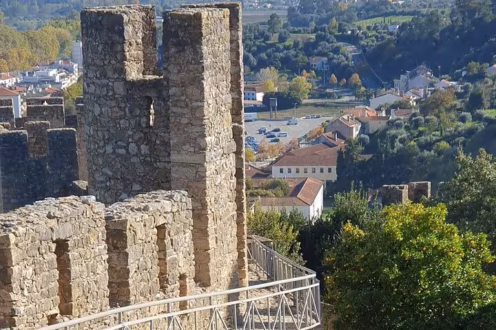 Ancient stone walls of Tomar Castle overlooking the scenic landscape and town below.