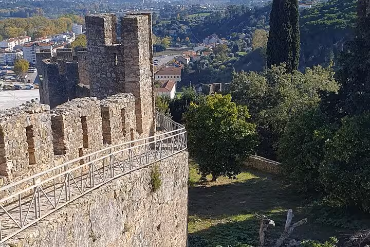 Scenic view from Tomar Castle's ancient stone walls overlooking the lush Portuguese landscape.