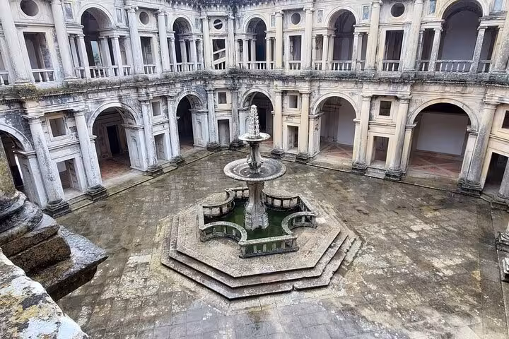 Explore the historic courtyard of the Convent of Christ in Tomar with intricate architecture on a walking tour.