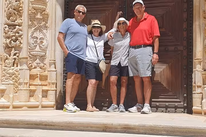 Group enjoying a sunny day at the ornate entrance of Tomar's historic Convent of Christ.