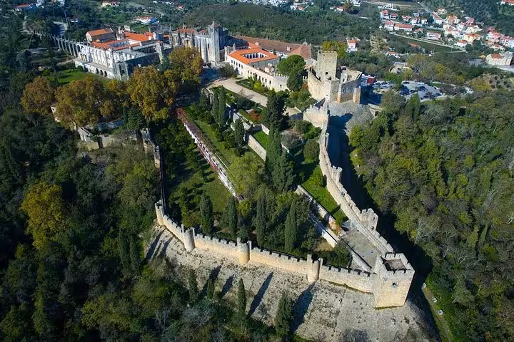 Aerial view of the Convent of Christ and surrounding lush landscapes in Tomar, highlighting the medieval architecture.