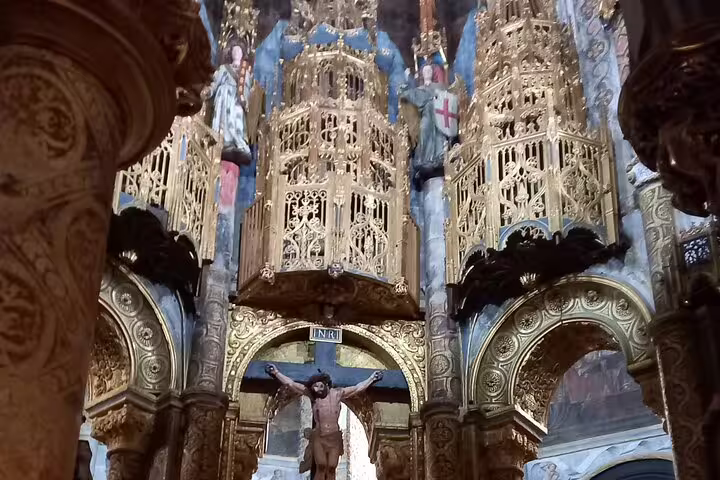 Intricate golden altar with crucifix inside Tomar's Convent of Christ, a highlight of Tomar-Coimbra day tour.