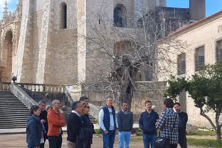 A group enjoys a guided tour outside the historic Convent of Christ in Tomar, highlighting its rich history.