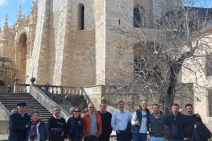 Group of tourists outside the Convent of Christ during a Tomar walking tour under clear blue skies.