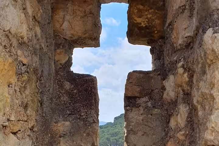 View through ancient fortress window at Tomar, showcasing lush landscape, perfect for historical tours in Portugal.