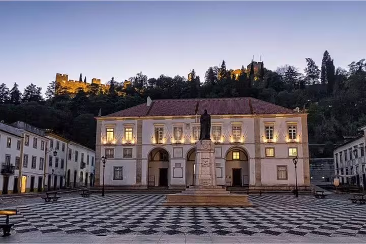 Historic square in Tomar, Portugal, featuring a statue and illuminated architecture, perfect for a day tour from Lisbon.