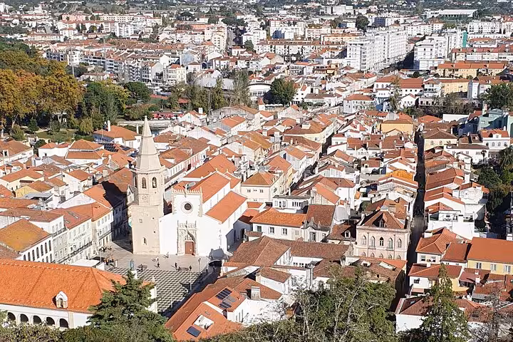Discover Tomar's charming historic town view with its iconic church towers, red-tiled rooftops, and vibrant cityscape.