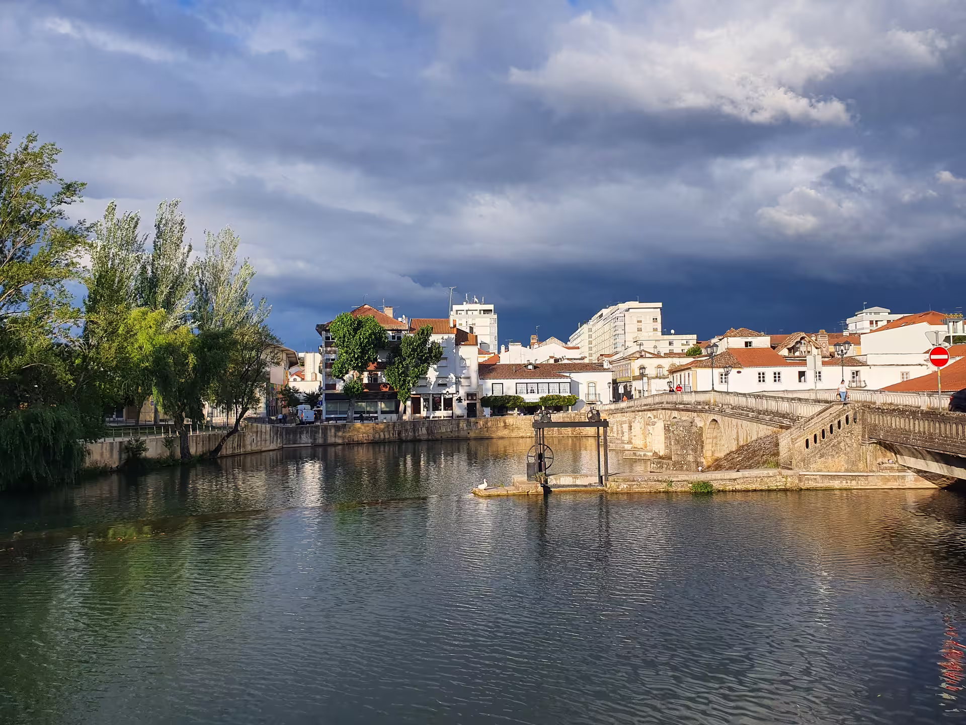 Scenic view of Tomar with historic buildings and a stone bridge over the Nabão River, featured on the Knights Templar tour.
