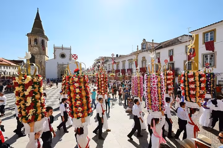 Vibrant festival in Tomar's historic square with participants in traditional attire, highlighting local culture and festivities.
