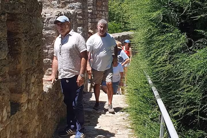 Tourists exploring historic stone pathways on a guided tour of Tomar, Portugal, surrounded by lush greenery.