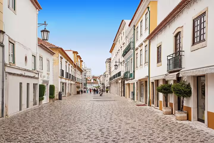 Charming cobblestone street in Tomar, Portugal, showcasing colorful historic buildings on a customizable private day trip from Lisbon.