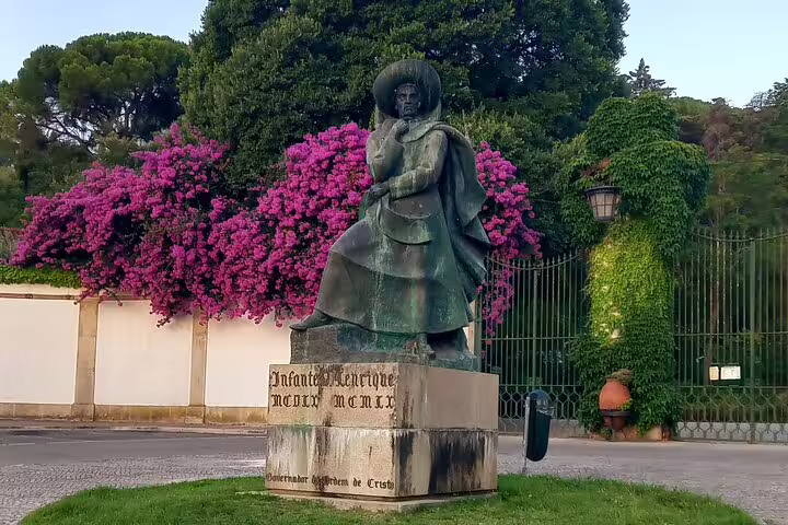 Statue of historic figure surrounded by vibrant flowers in Tomar, a highlight on the 2-day tour including Coimbra.