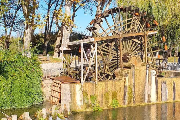 Discover the charming rustic waterwheel nestled in Tomar's lush riverside park on an authentic local tour.