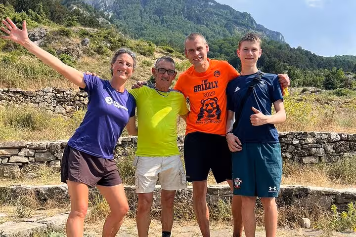 Group of hikers smiling and posing in front of a mountainous landscape during the Tomor Mountain Lakes of Dardhe adventure tour.