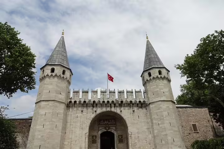 Entrance gate of Topkapi Palace featuring historical architecture and Turkish flag on Istanbul Galataport tour.