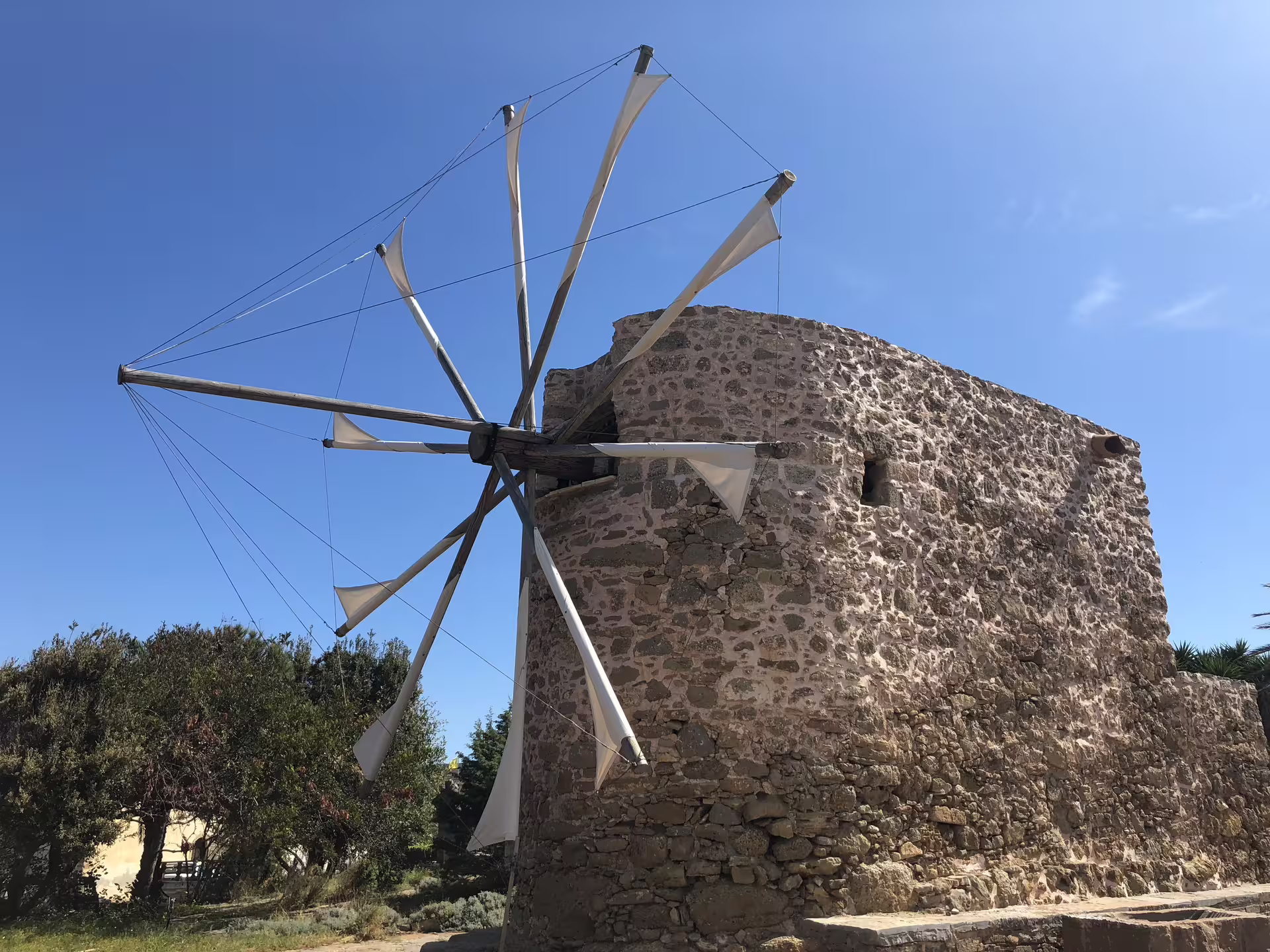 Historic windmill at Toplu Monastery under clear blue skies, capturing the essence of Crete's cultural heritage.