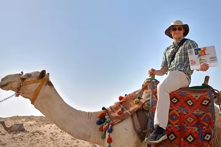 Tourist riding a camel in Egypt desert, part of Hurghada to Cairo Pyramids and Grand Egyptian Museum tour