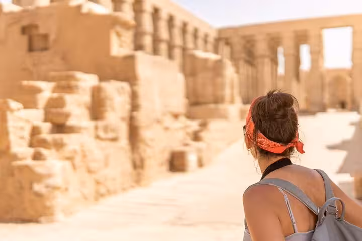 Tourist with backpack exploring Karnak Temple ruins on Luxor small group tour from Cairo by plane