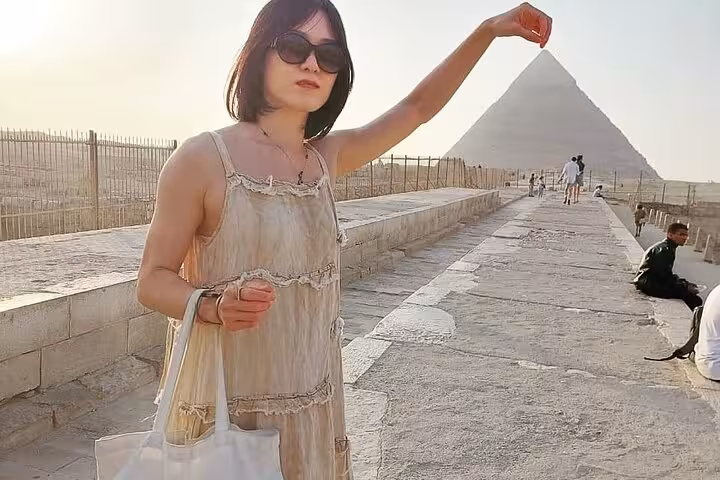Tourist posing on Giza plateau walkway with pyramid view, Cairo private tour with photo opportunities