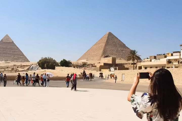 Tourist photographing the Giza Pyramids on a Cairo full-day customized tour with optional camel ride
