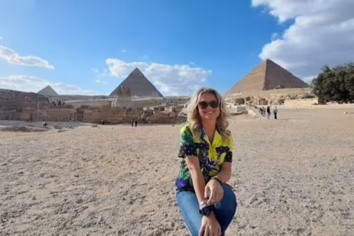 Smiling tourist at Giza Pyramids plateau on VIP all-inclusive Cairo day tour with camel ride and photo stops