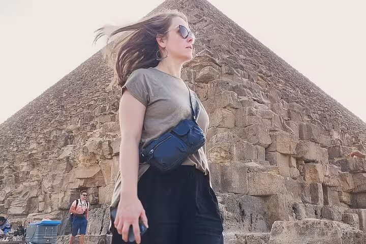 Tourist in sunglasses at the Great Pyramid of Giza, part of a private Cairo tour including Citadel, bazaar and felucca