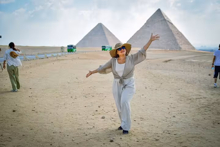Tourist posing in front of the Great Pyramids of Giza on a full-day Cairo trip from Sharm by bus