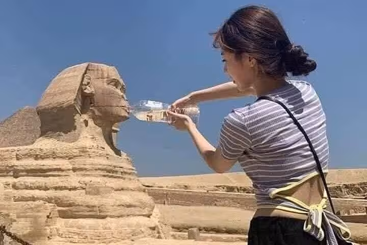 Tourist posing with Great Sphinx of Giza on a private half-day tour with guide, Cairo desert backdrop