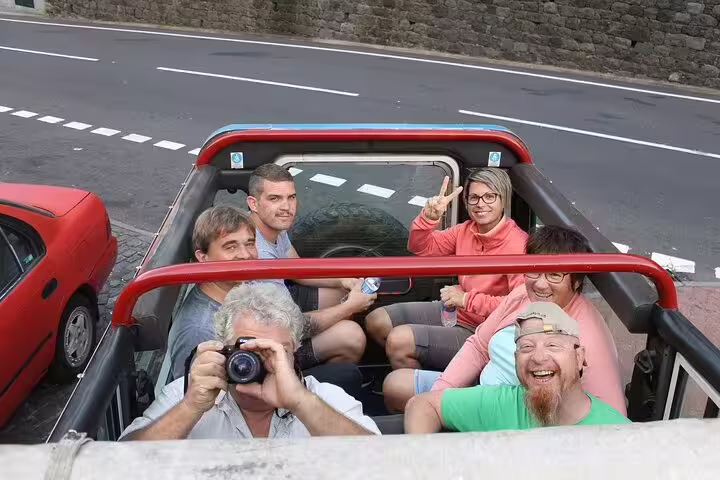 Group of tourists enjoying a Full Day Private 4x4 Adventure in Madeira, smiling and capturing memories in an open-top vehicle.