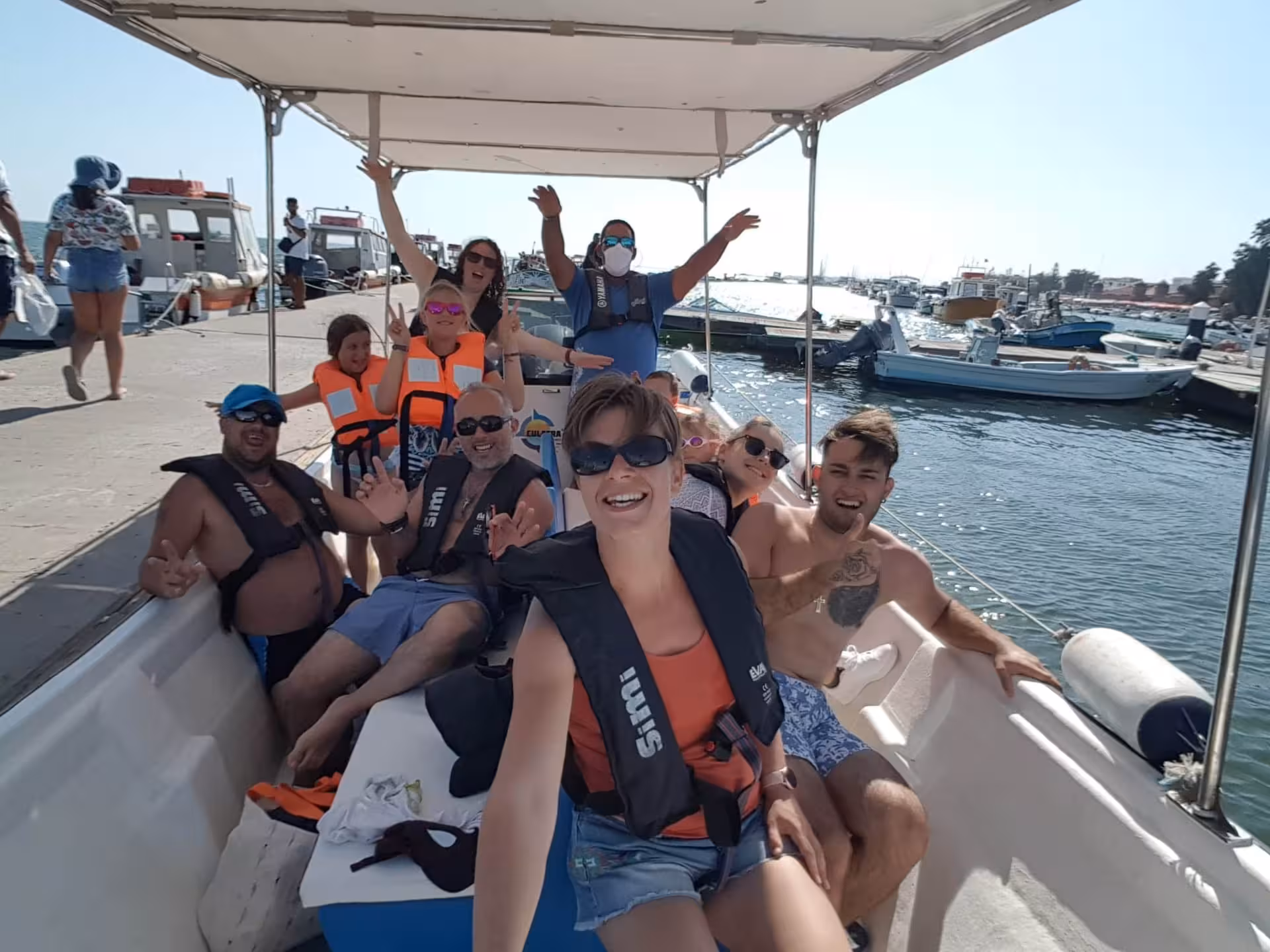 Tourists smiling and waving on a boat excursion to Culatra Island, experiencing a fun-filled day on the water.