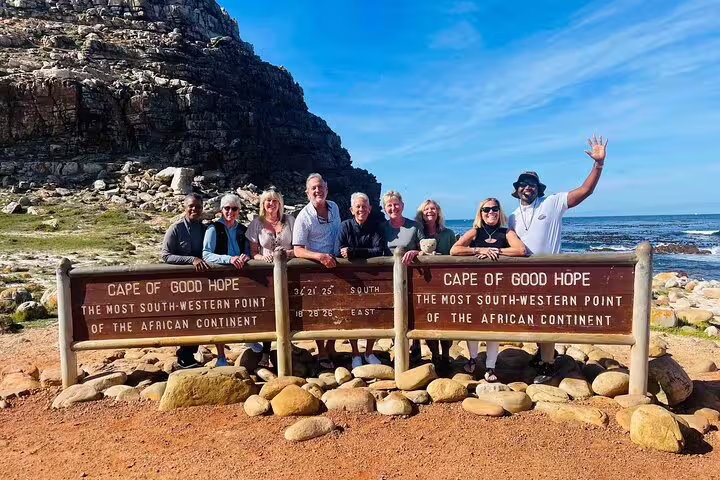 Group of tourists at Cape of Good Hope sign, enjoying scenic views on Half Day Penguins and Cape of Good Hope Tour.
