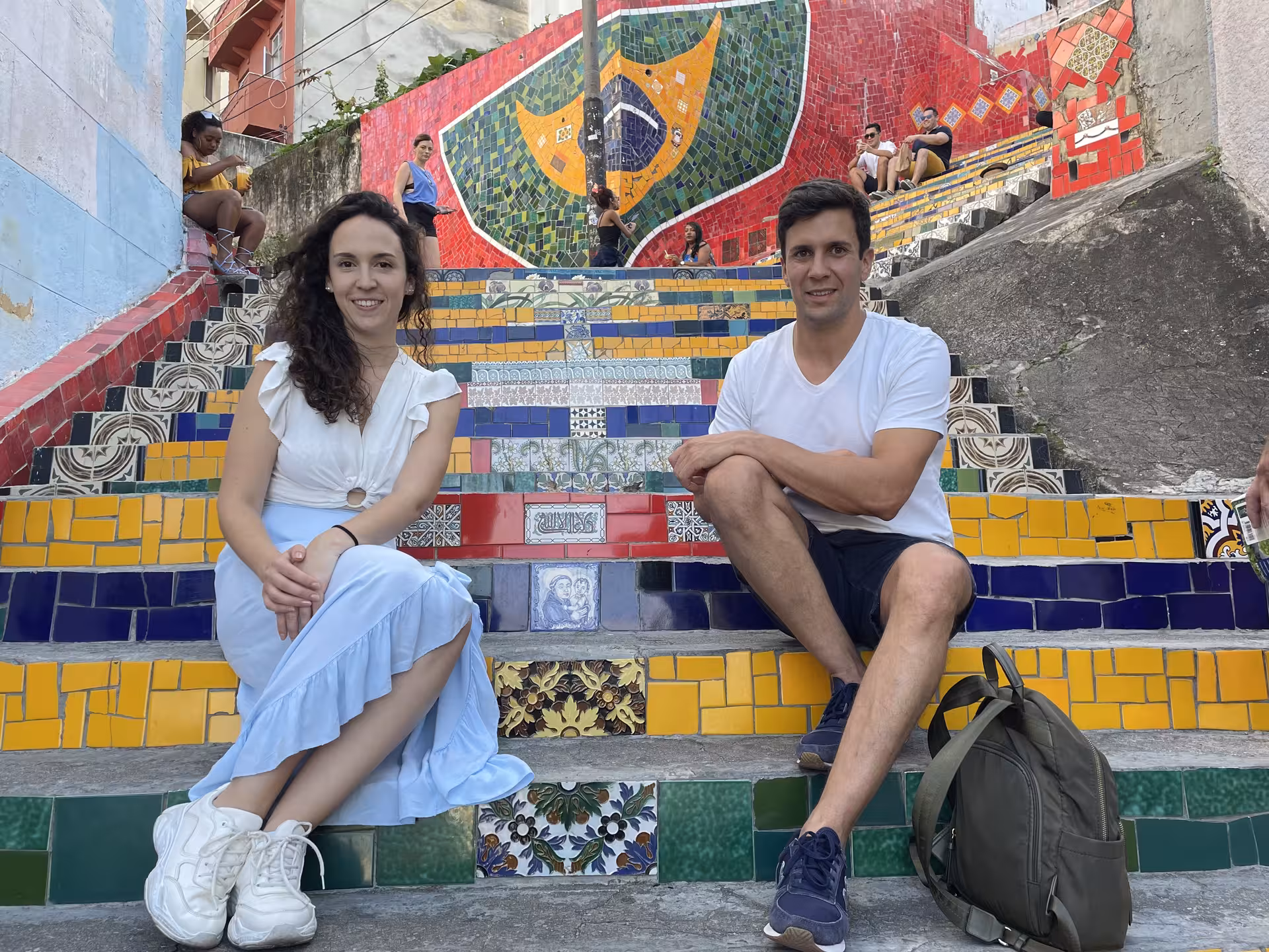 Tourists sitting on colorful Selarón Steps in Santa Teresa, part of guided tour in Rio.