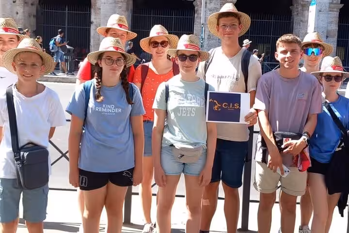 A group of tourists wearing straw hats, ready to explore Rome's Colosseum and Roman Forum.
