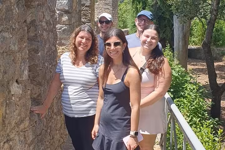 A group of tourists smiles while exploring historic stone architecture in Tomar on a guided tour.