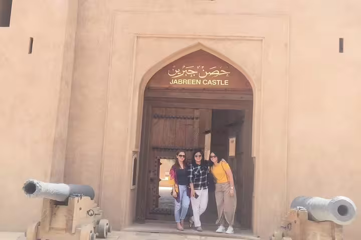 Group of tourists standing at Jabreen Castle's entrance, part of the Muscat full day private tour to Nizwa.