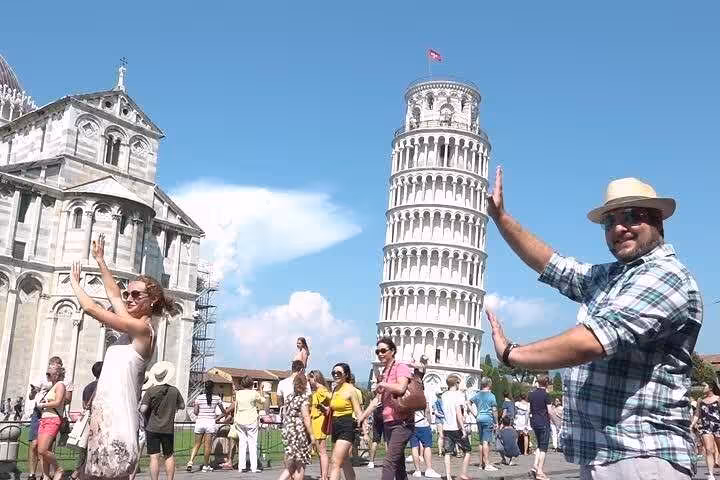 Tourists posing with the Leaning Tower of Pisa, capturing playful photos on the full-day Lucca and Pisa tour.