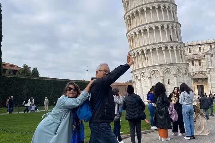 Tourists posing playfully with the Leaning Tower of Pisa, capturing the iconic architectural marvel.