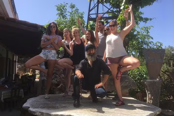 Group of tourists posing for a photo at a pottery workshop in Kritza, Crete, surrounded by greenery.
