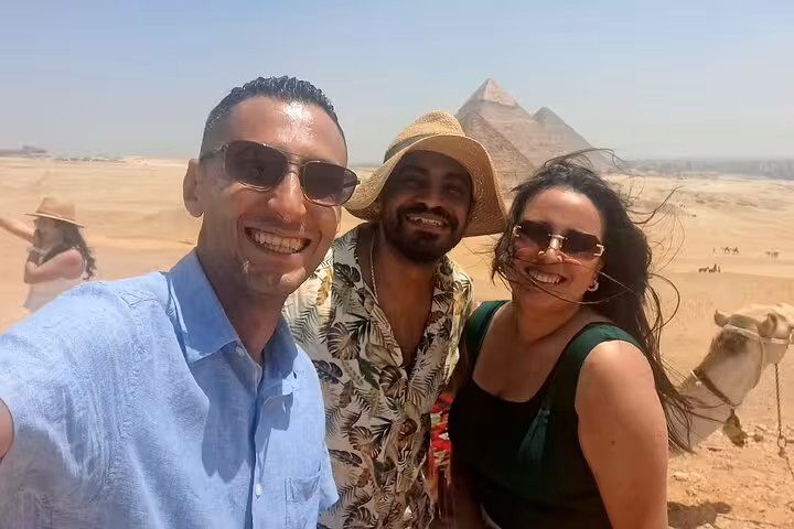 Smiling tourists enjoying the view of the Pyramids of Giza on a sunny day during a private Cairo tour.