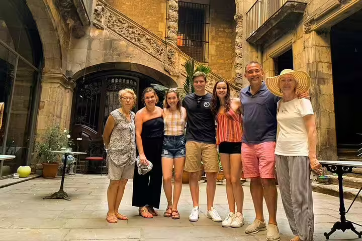 A group of tourists smiles in a historic courtyard during a Tapas, Wine, and Flamenco Private Tour in Barcelona.