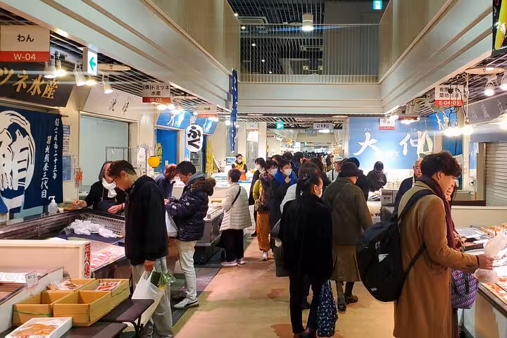 Visitors exploring fresh seafood stalls inside the bustling Toyosu Fish Market in Tokyo on a guided tour.