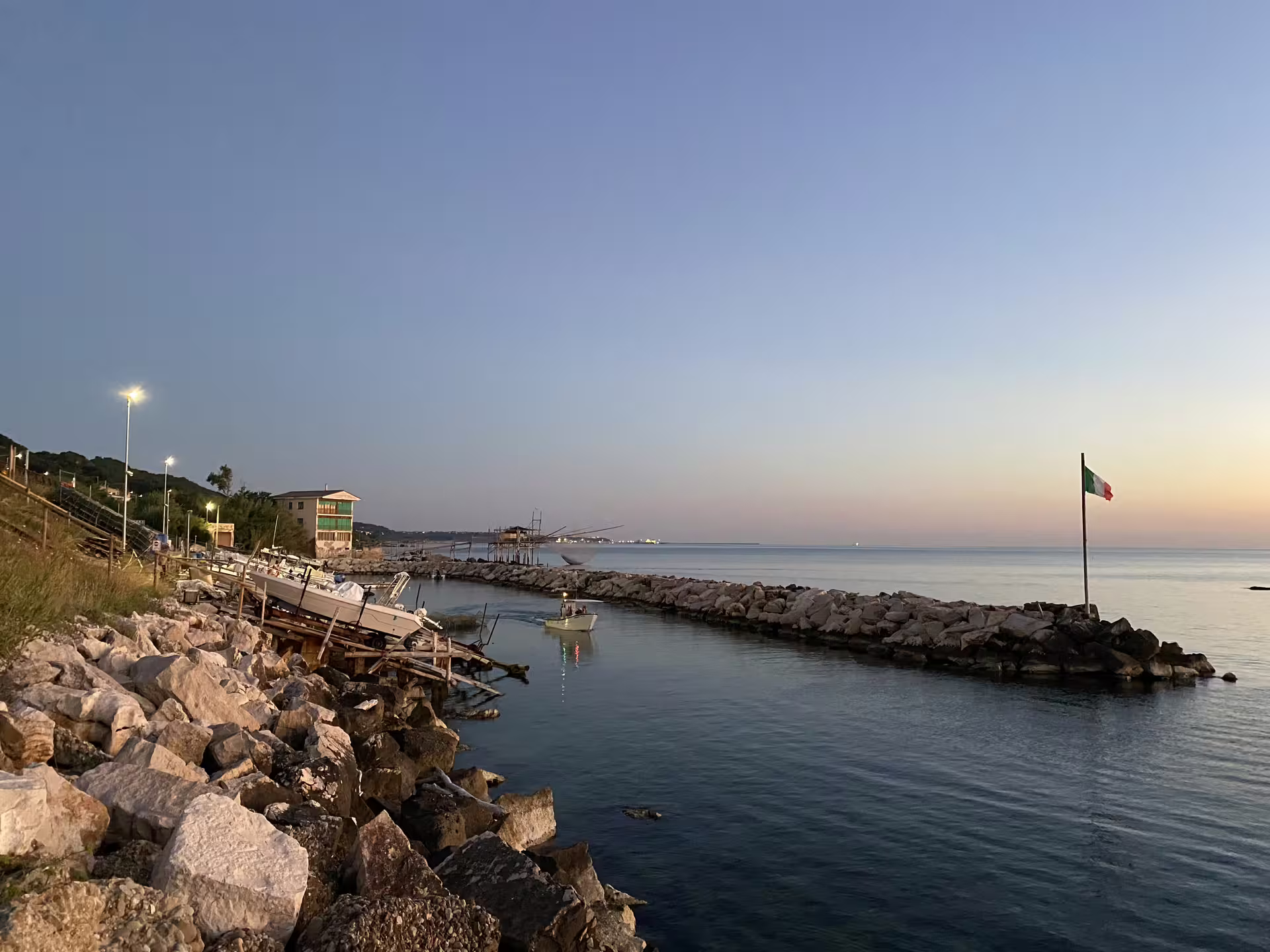 Evening harbor on the Trabocchi Coast with boats and Italian flag, Abruzzo fishing tourism experience